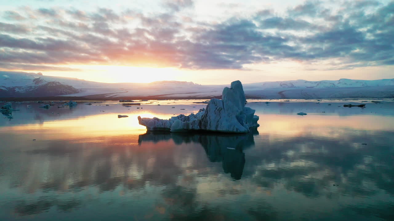 Iceberg Floating On A Calm Lake At Sunrise In Jokusarlon Glacial Lake In South Island - Drone Orbiting Shot