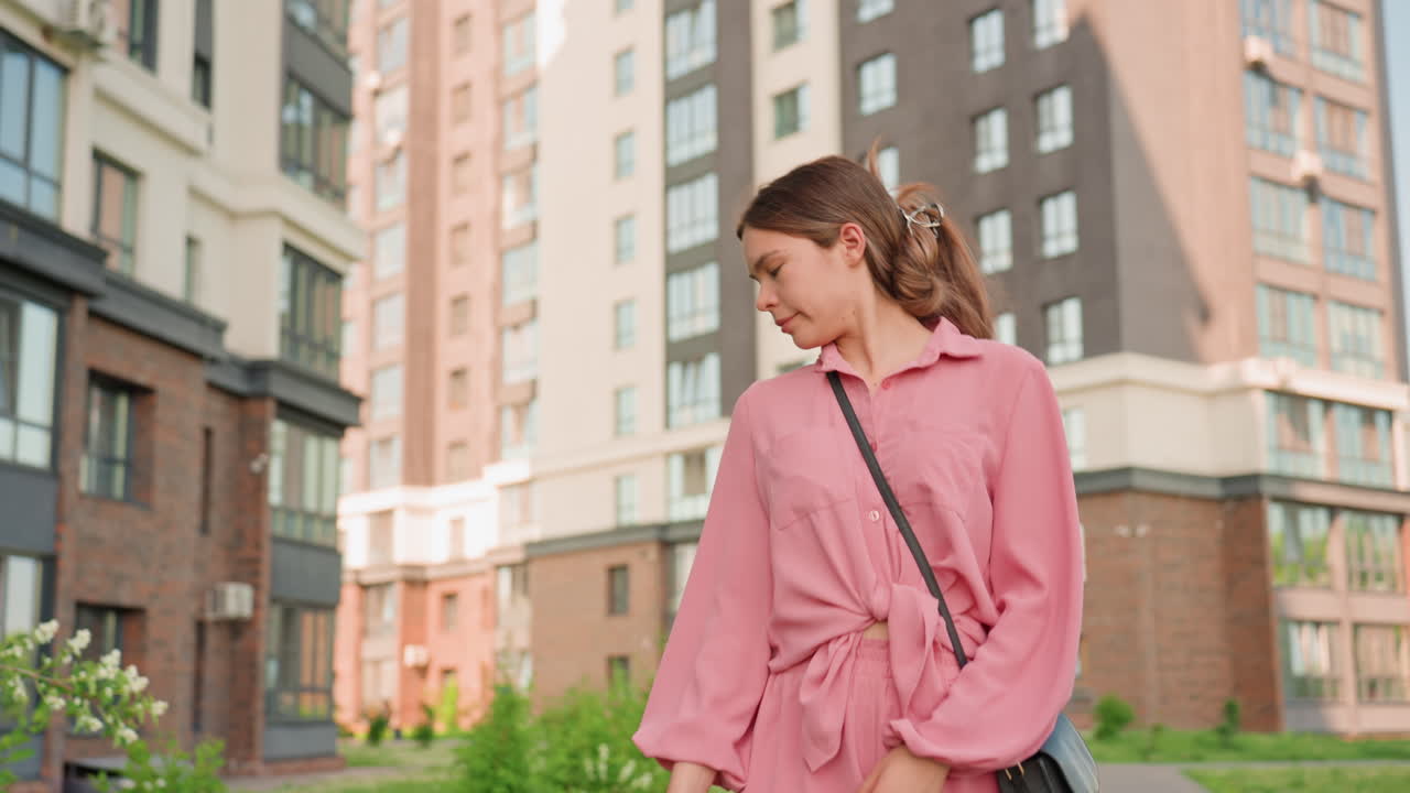 Young Lady With Leash Outdoors, Thoughtful Young Woman Stands Near Residential Greenery With Leash, Casual Young Woman In Pink Outfit Holding Leash Beside Green Residential Area Under Daylight