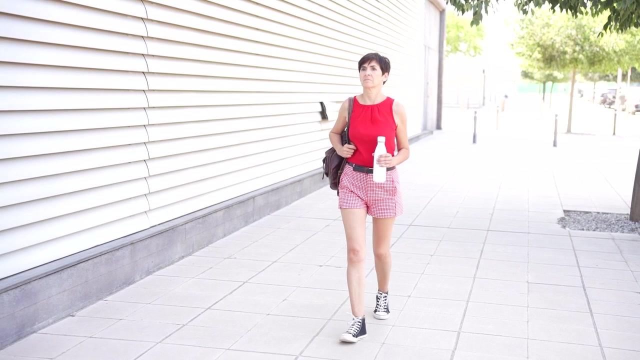 Seorang wanita muda stylish mengenakan pakaian urban chic berpose di depan arsitektur modern.