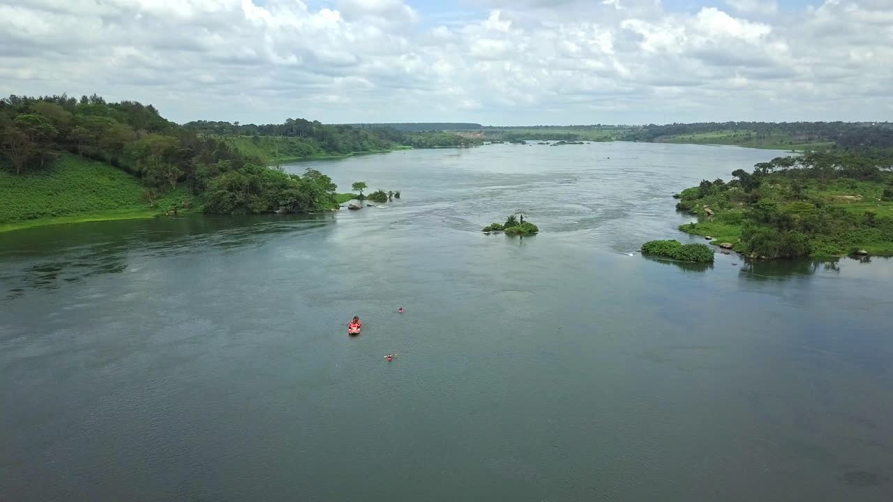 Drone push-in over white water rafting on the Nile River near Jinja, Uganda. Rafters descend rapids amid spray, rocks, and lush riverbanks in one of Africa’s top adventure destinations