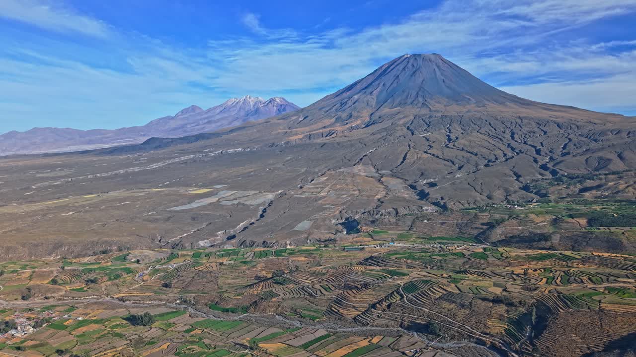 Ripresa aerea panoramica a volo radente con drone del Misti e del Chachani, Perù, che cattura le colate laviche che dal Misti scendono a cascata verso gli estesi terreni agricoli terrazzati; il movimento panoramico enfatizza la scala e il contrasto nelle spettacolari Ande