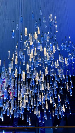 unique lighting design in modern venue. a creative light installation features hanging glass fixtures in varying heights, illuminating a vibrant atmosphere