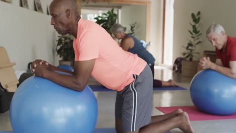 focused diverse seniors using exercise balls in pilates class, unaltered, in slow motion