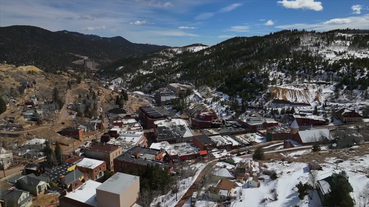 Historic downtown buildings Central City Black Hawk Colorado aerial drone view city townhall winter sunny daytime blue sky Gold mining town tailings neighborhood streets casinos forward pan up motion