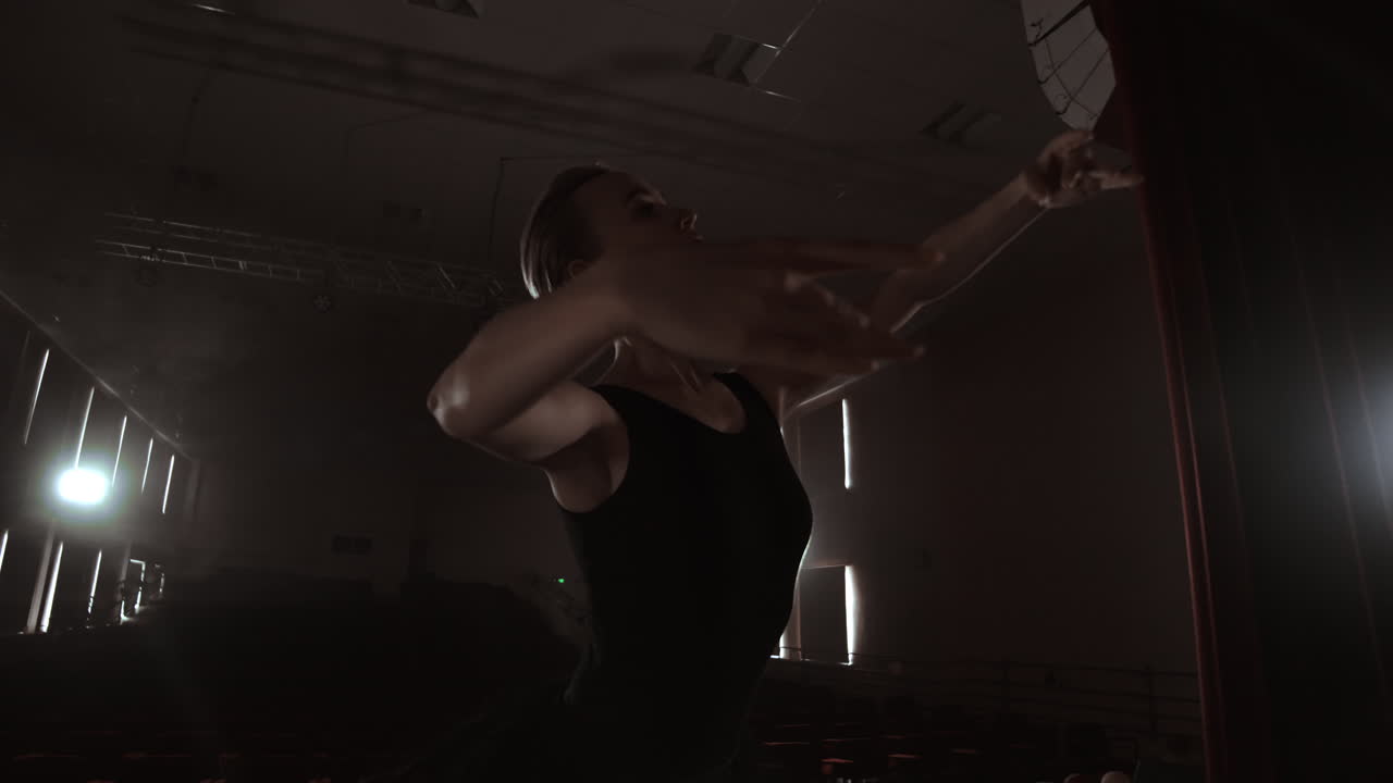 Silhouette of young ballet dancer standing back to camera. Light silhouette of elegant young ballerina standing back to camera in second position arms pose on