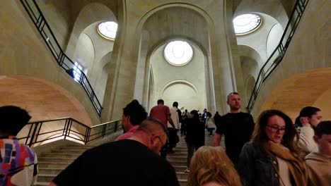 people climbing stairs inside louvre museum, paris