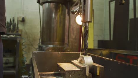 caucasian male hands factory worker at a factory standing at a workbench and operating a bench drill