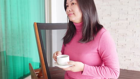 Close-up-Asian-woman-relaxing-on-a-pool-bed-and-drinking-coffee-by-her-private-pool-during-her-morning-vacation