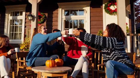 diverse friends gathering and cheering with mugs on an autumn porch