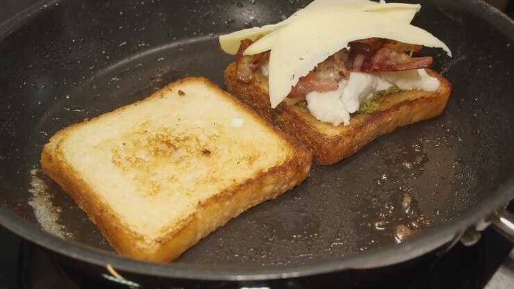 Thin slices of Swiss cheese added to thick fried breakfast sandwich