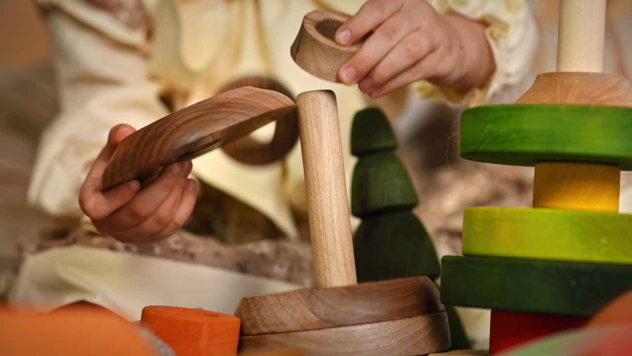 Little girl's hands playing with a wooden stacking jug. Ecological and sustainability concept