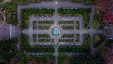 a symmetrically designed garden with central fountain at dusk, aerial view