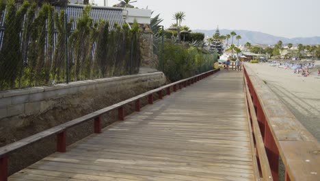 the boardwalk along the beach of cala de mijas on a beautiful sunny day with a couple of people walking in the distance