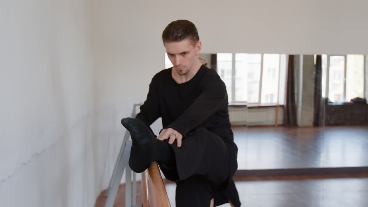 Man Stretching at a Ballet Barre in a Dance Studio