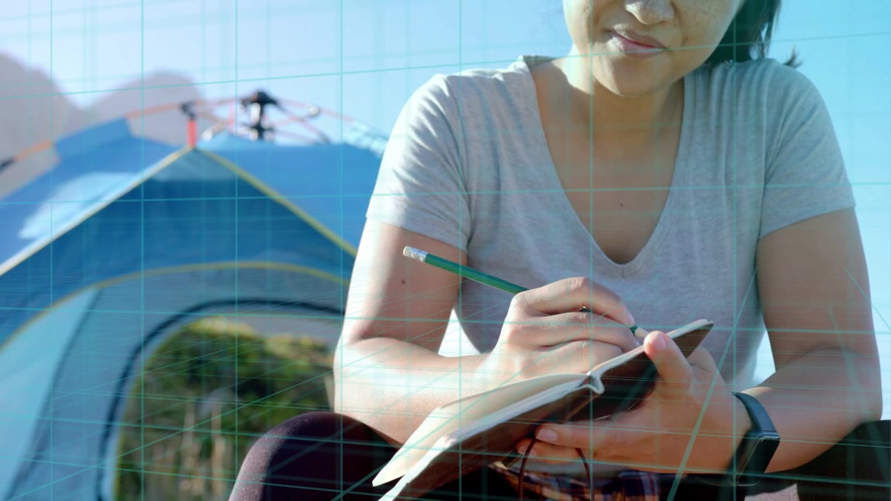 Mujer escribiendo un diario de viaje en un campamento, cámara moviéndose de las manos al rostro, superposición de cuadrícula mostrando un dron