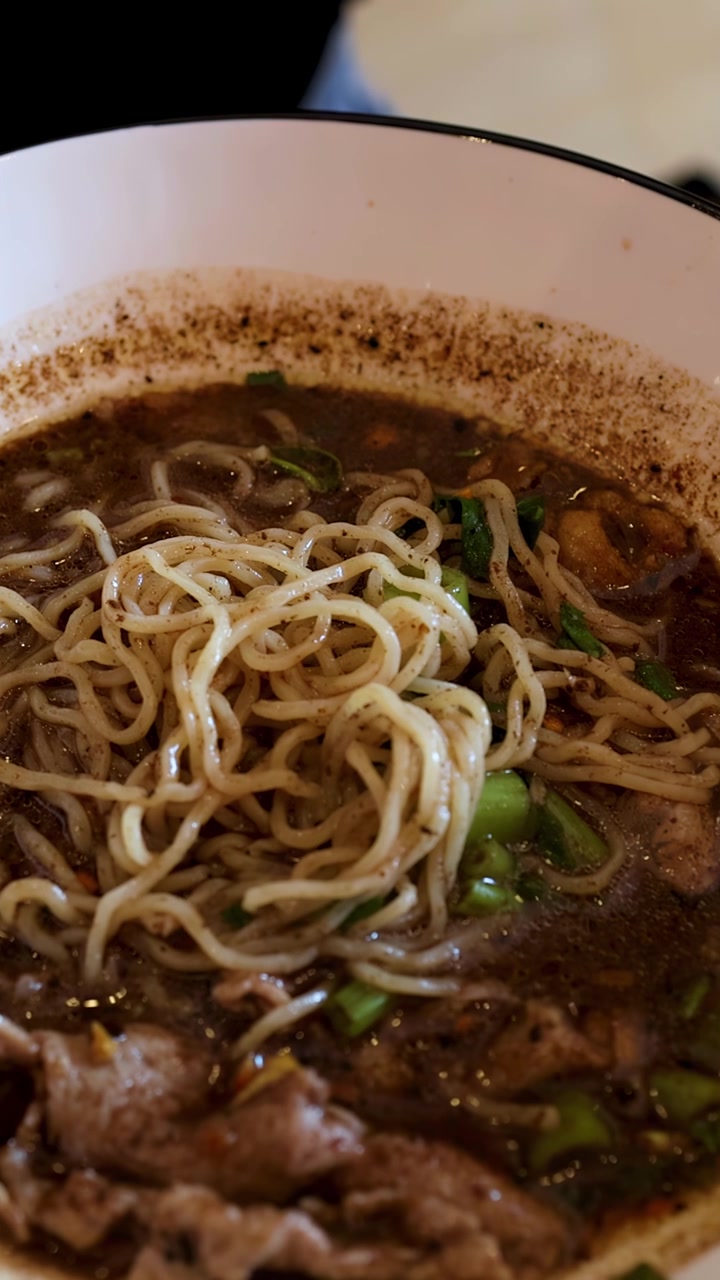 Un primo piano di noodles tailandesi con vermicelli di riso, maiale e una ricca zuppa scura