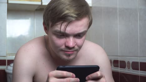 man using phone in bathroom toilet