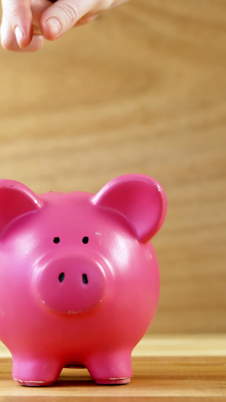 la mano dejando caer la moneda en la alcancía