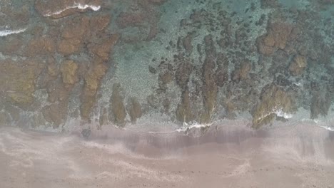 Aerial-view-with-drone-over-a-southern-Spanish-beach-in-Marbella,-Andalusia,-Spain,-calm-waves-on-crystal-clear-water