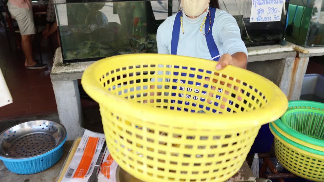 persona pesando artículos en una balanza de canasta amarilla