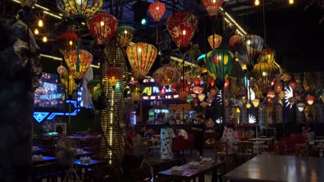 vietnam,danang, a restaurant decorated with colorful chineese lanterns, some people sitting on the tables, a waiter is walking by, colorful lights all around.