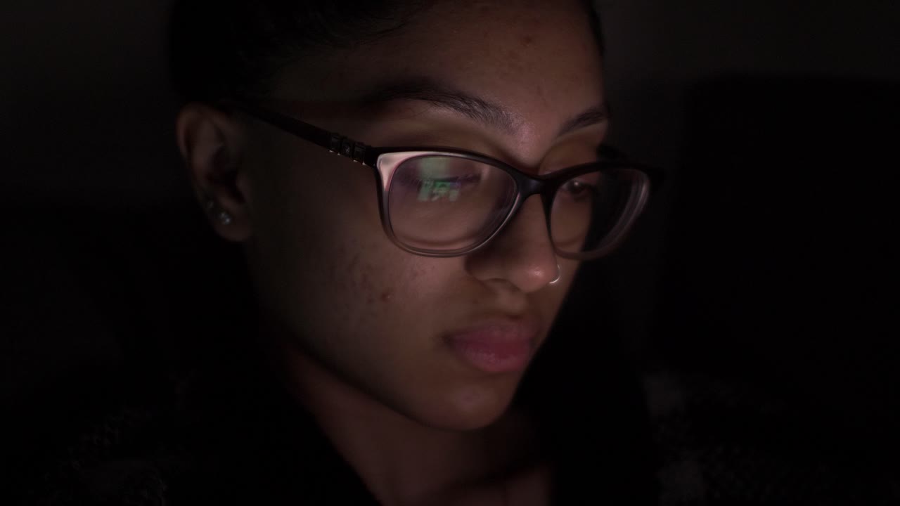 Young UK Asian Female Browsing Mobile At Night