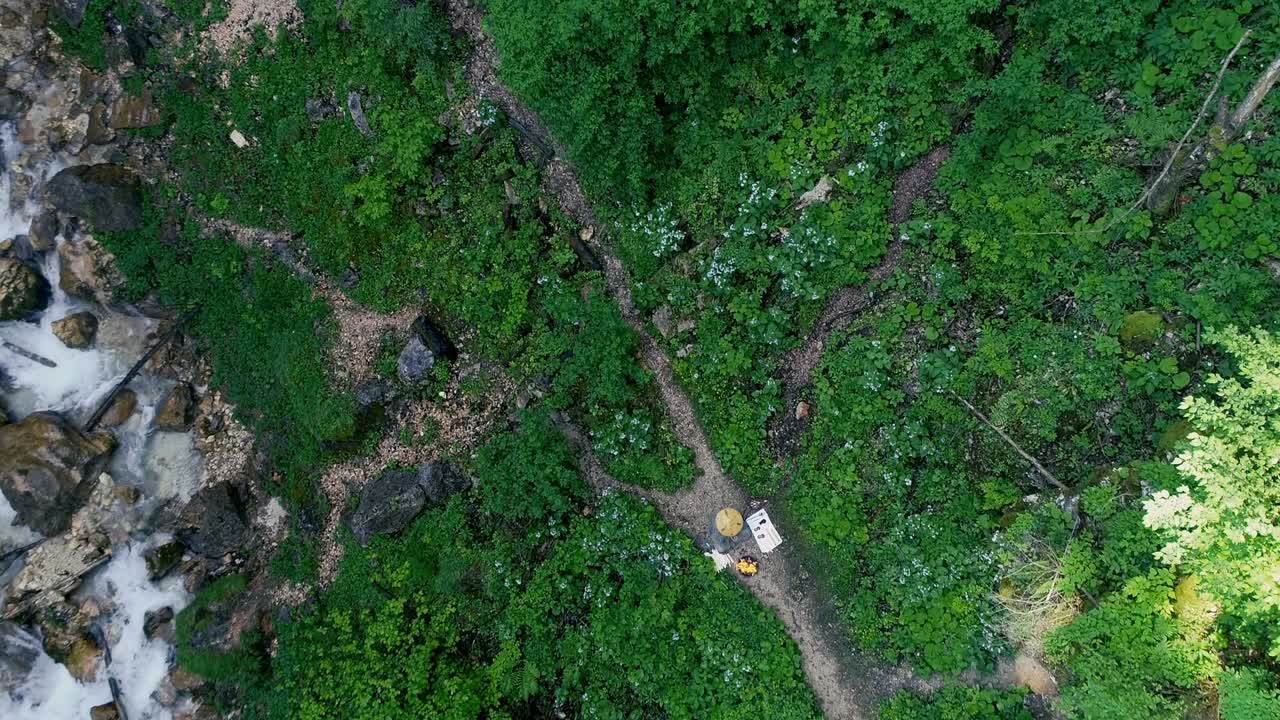 hombre con barba hace una ceremonia de fuego frente a una gran cascada