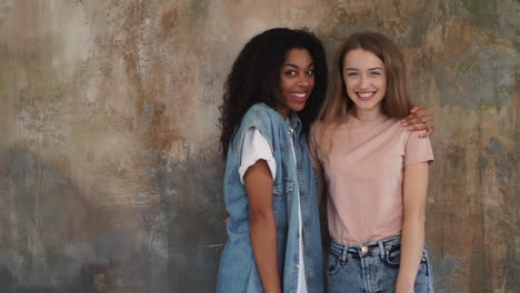 black girl and caucasian young woman hug each other with affection. two loving friends laugh together. medium shot.