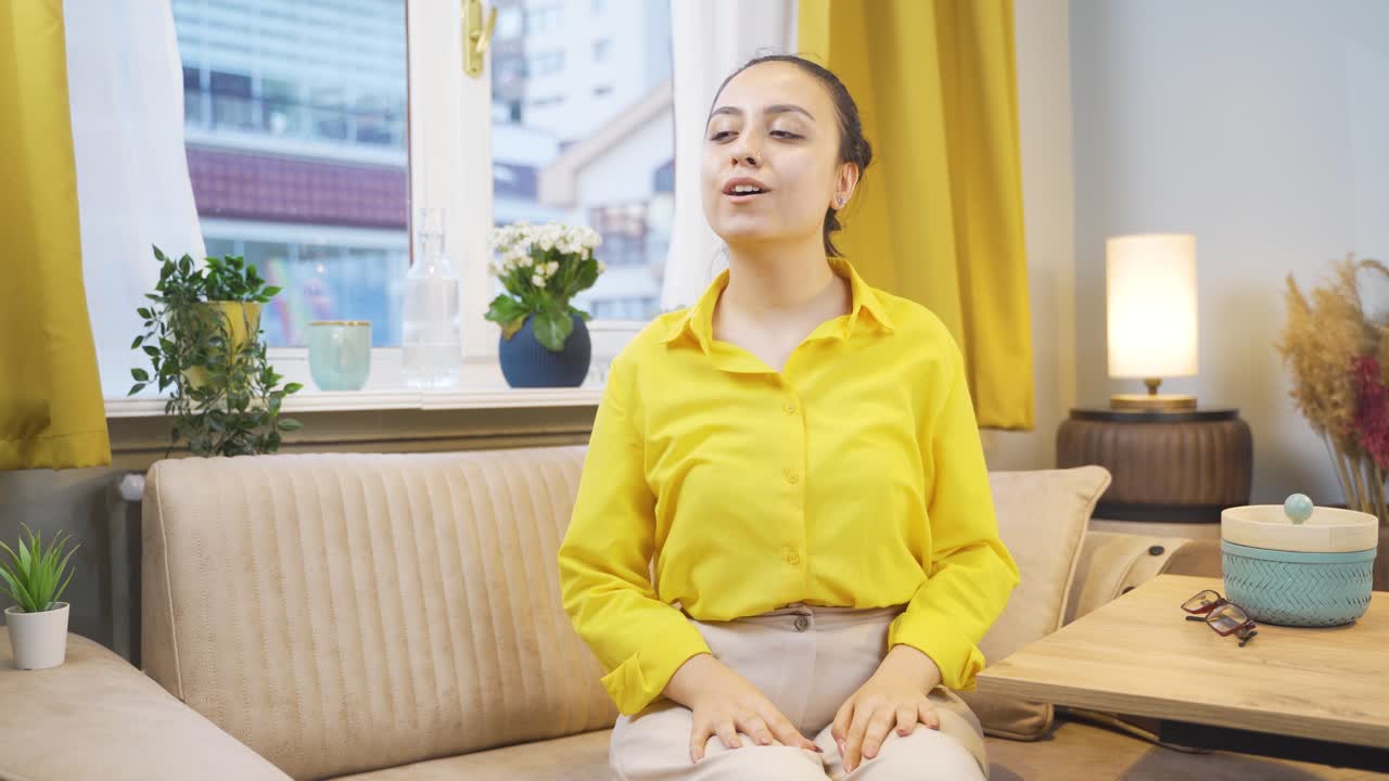 행복한 젊은 여자는 창문 밖을 바라보고 깊은 숨을 쉬고 있습니다.