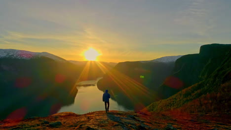 aerial view of person on peak mountain watching sunset on lake after hike