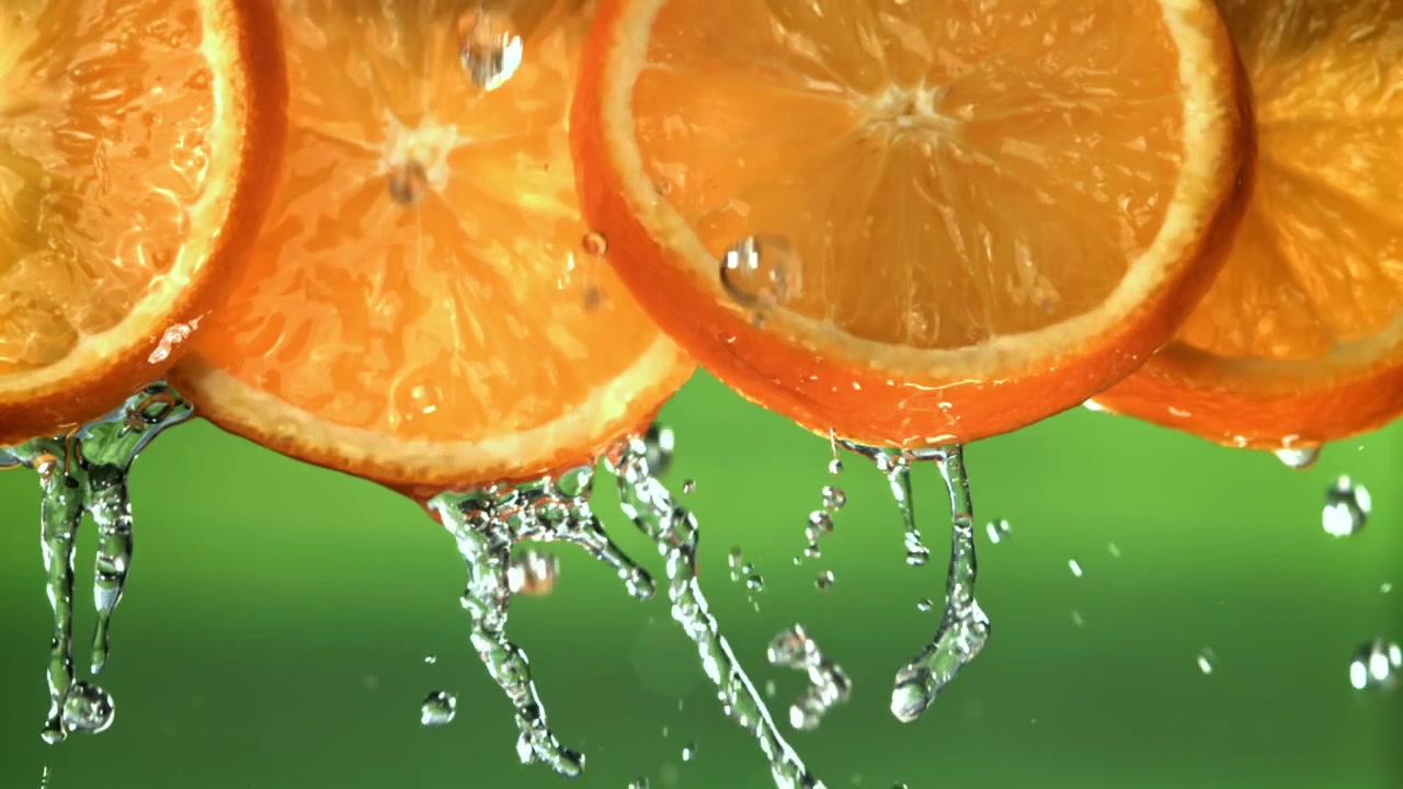 Gocce d'acqua rinfrescanti su vivaci fette d'arancia al rallentatore
