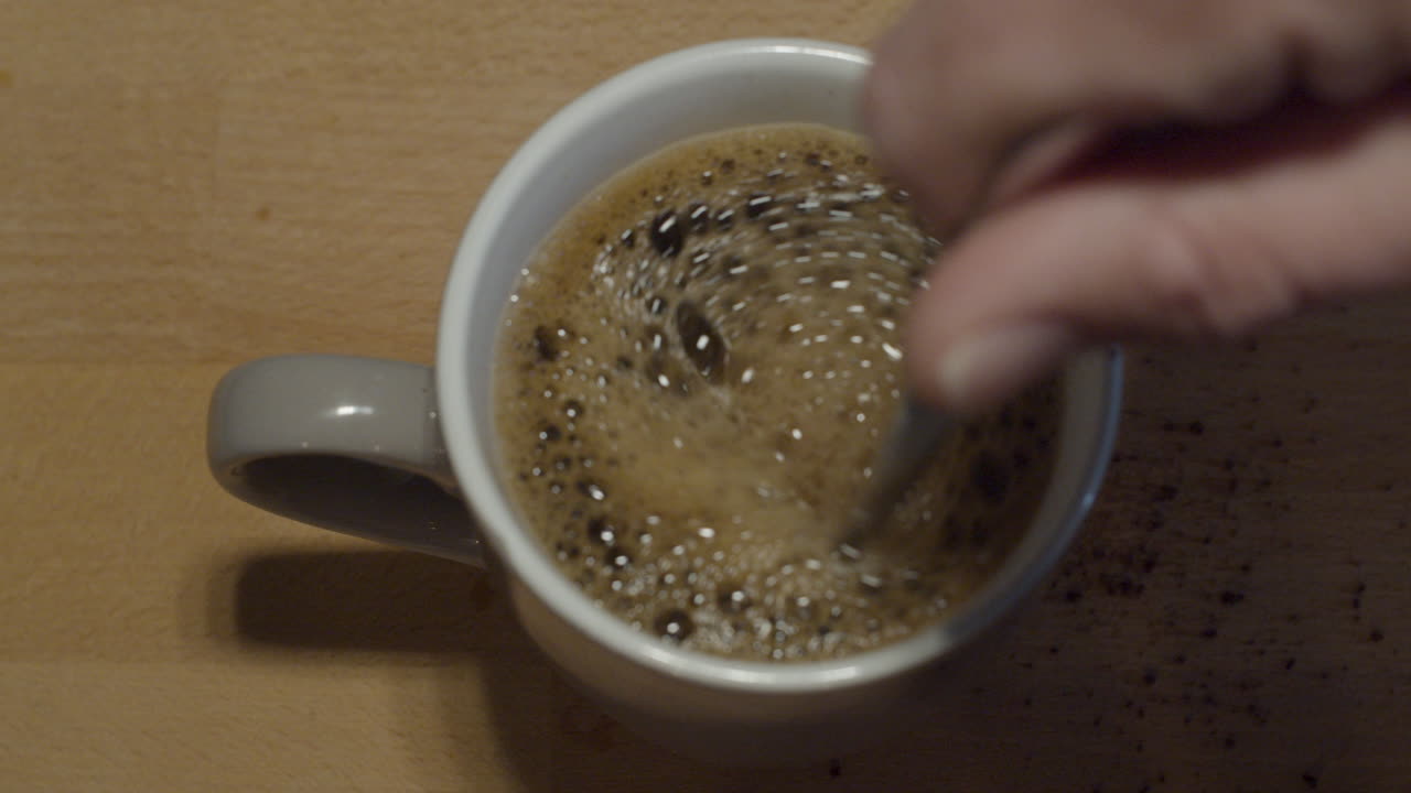 Ripresa dall'alto di una mano che mescola una tazza di caffè
