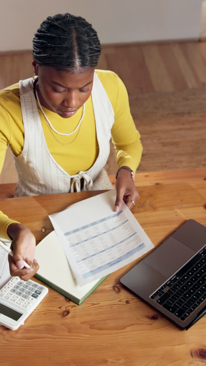 Woman working at desk with laptop, notebook, and documents