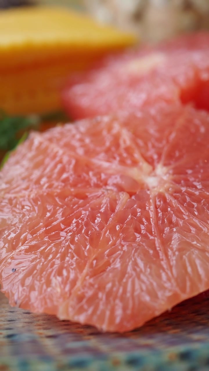 Primo piano di spicchi di pompelmo rosa appena sbucciato