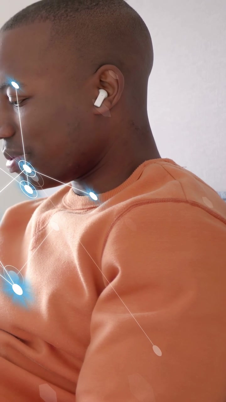 Video verticale: Uomo che parla con un auricolare, generando nodi blu che mappano viso e petto per scopi tecnologici.