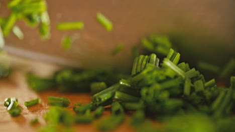 macro-shot-of-a-male-hand-chopping-fresh,-green-chives-on-a-wooden-cutting-board