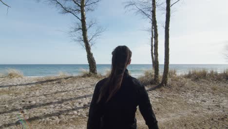 Junge-Frau-Beobachtet-Den-Horizont-Des-Ozeans-Und-Schaut-Sich-In-Der-Tropischen-Strandlichtung-Um