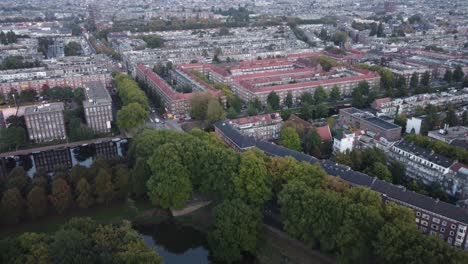 네덜란드 암스테르담(amsterdam)에서 멀어지는 공중 전망을 통해 운하와 전형적인 가옥의 건축물과 잎이 무성한 녹색 공원을 볼 수 있습니다.
