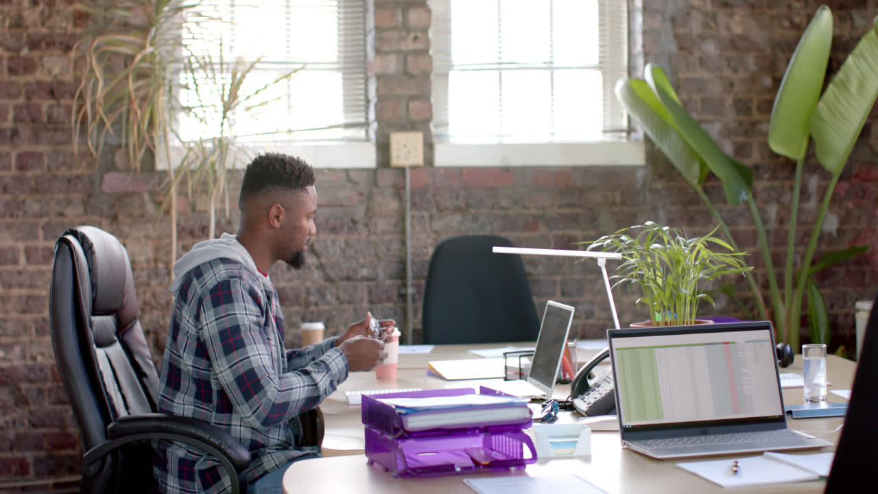 Focused african american casual businessman using laptop in office in slow motion