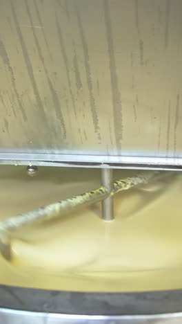 Butter production. Automated equipment mixing dairy product for making butter. Process of making fresh butter on a milk farm. Close-up.. Vertical video