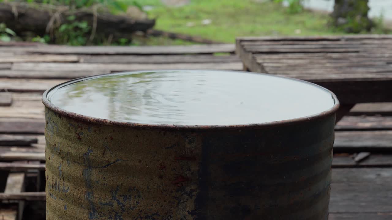 A rusty metal barrel filled with water on a wooden platform
