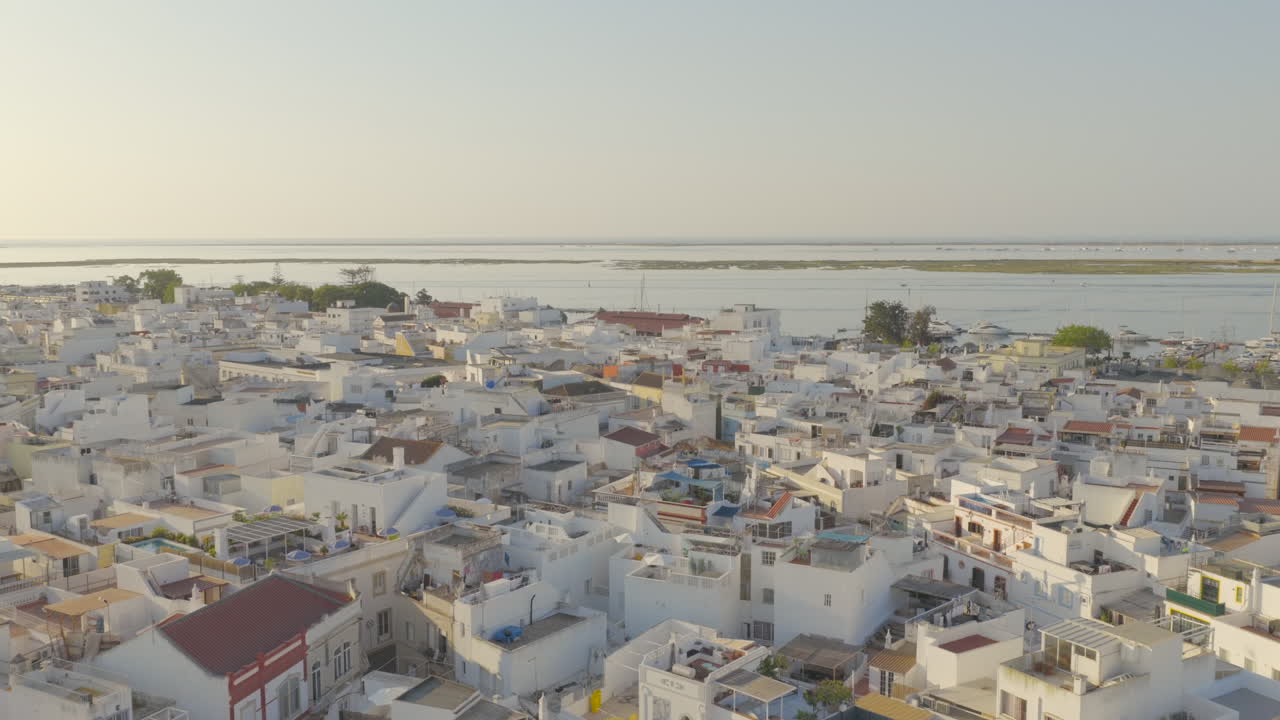 Un drone si muove sopra i tetti bianchi di Olhão all'alba verso l'iconico mercato e la laguna