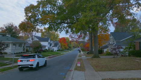 a car going down the street in a nice neighborhood pulls into a driveway as camera follows