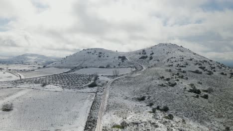 Drone-rising-aerial-view-of-snow-covered-Mount-Shifon-and-vineyard-fields-,-Israel