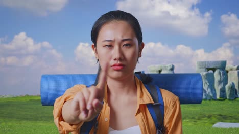 close up of asian female hiker with mountaineering backpack showing no gesture with index finger while traveling in stonehenge