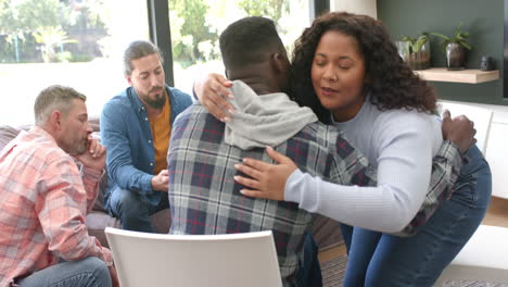 Two diverse male and female friends hugging in group therapy session