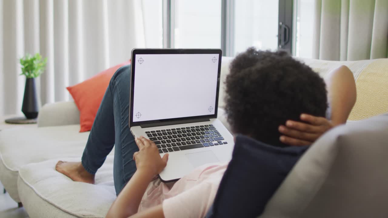 Happy african american woman sitting on sofa, using laptop with copy space