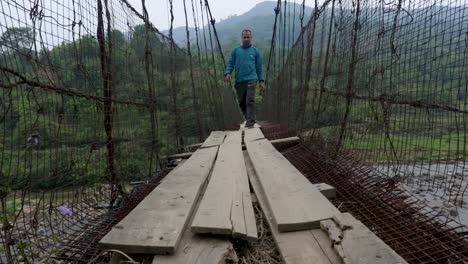 young man walking at vintage iron suspension bridge at morning from flat angle