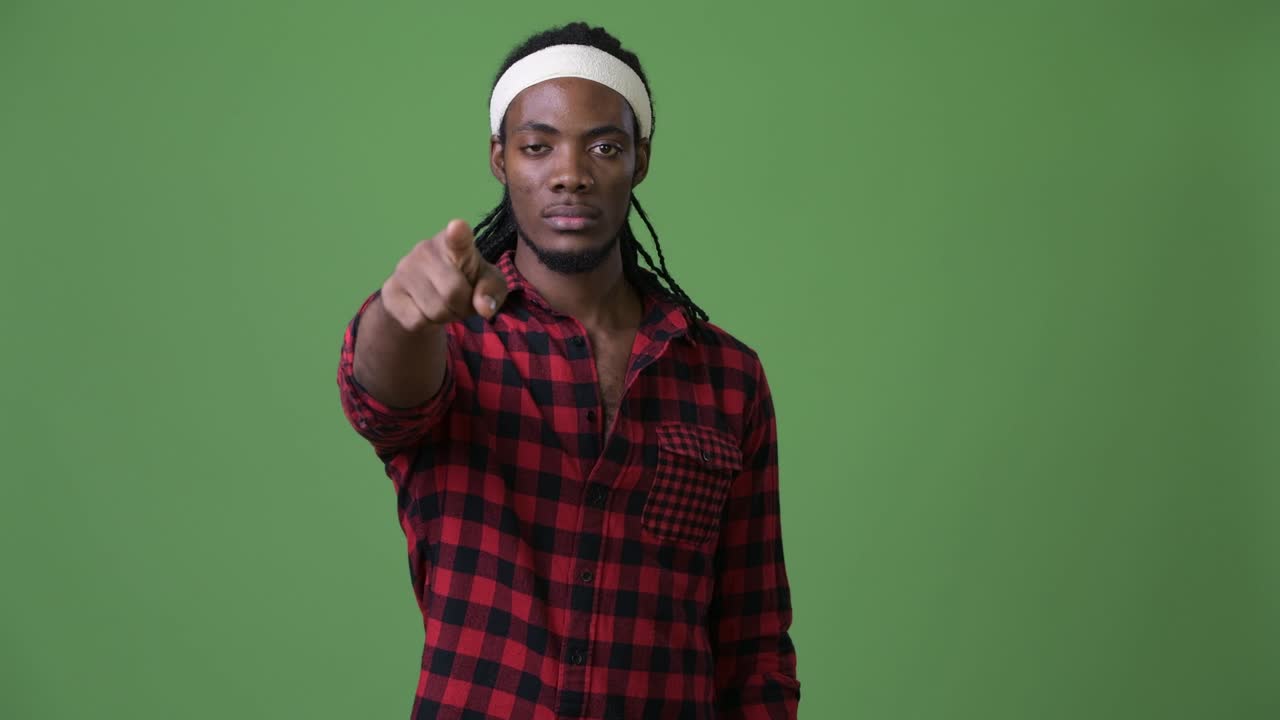 joven hombre africano guapo con dreadlocks contra un fondo verde