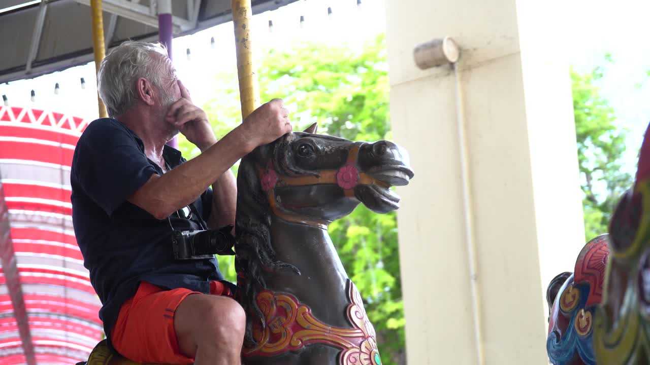 여름에 놀이 공원에서 함께 카루셀을 타는 행복한 부부, 미치광이 노인과 웃긴 성숙한 여성이 휴가에서 즐거움을 얻습니다.